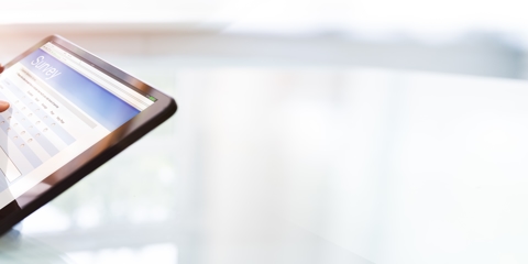 Hand working on a digital tablet on a shiny white tabletop