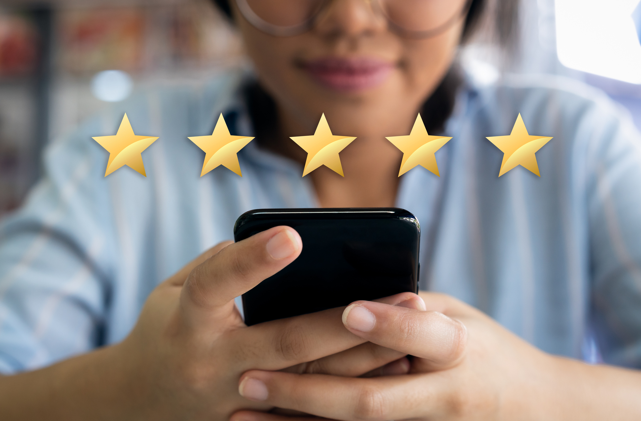 Woman looking at cell phone with five stars above the phone